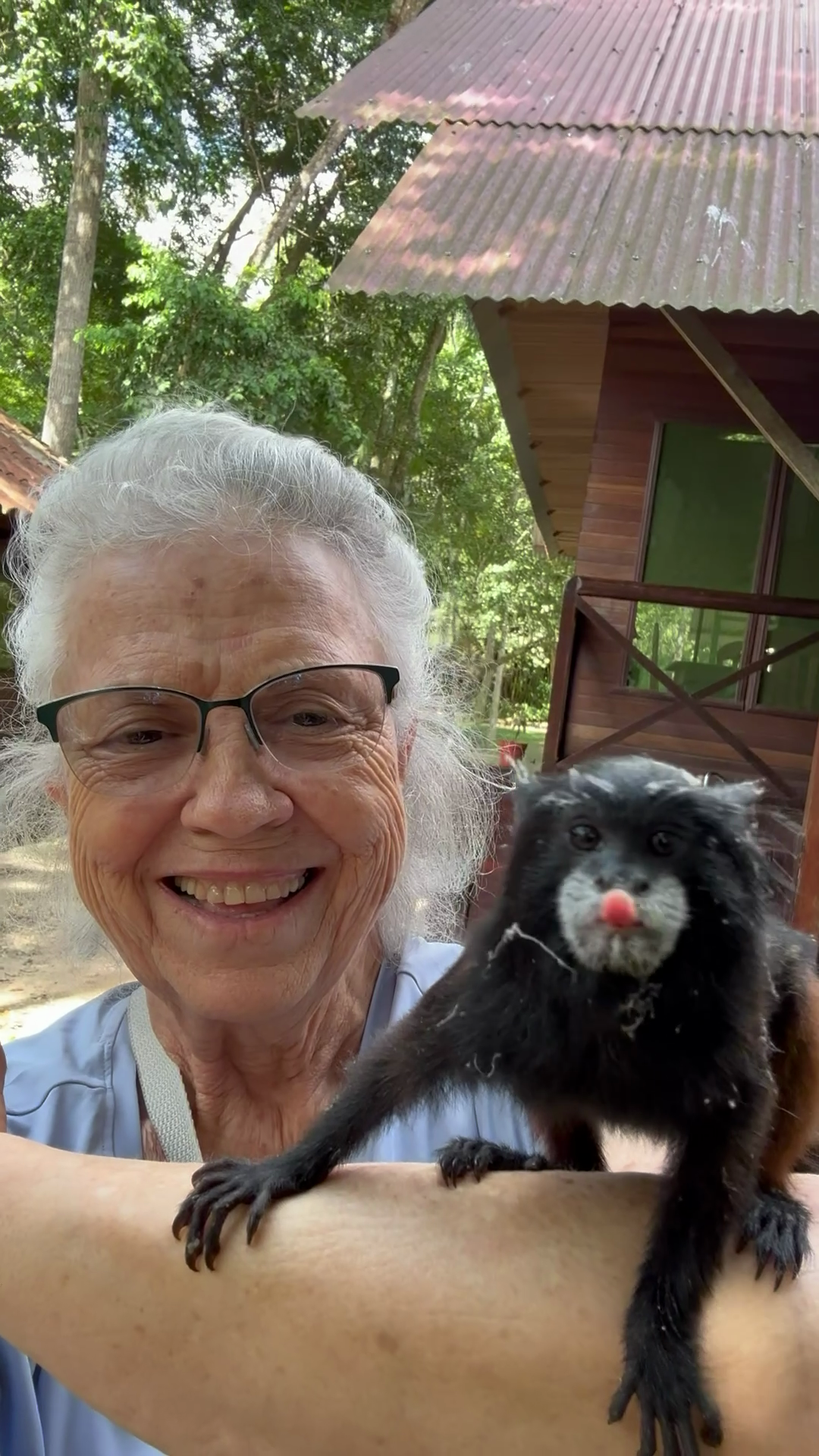 Isara smiling with a marmoset perched on her arm in Peru